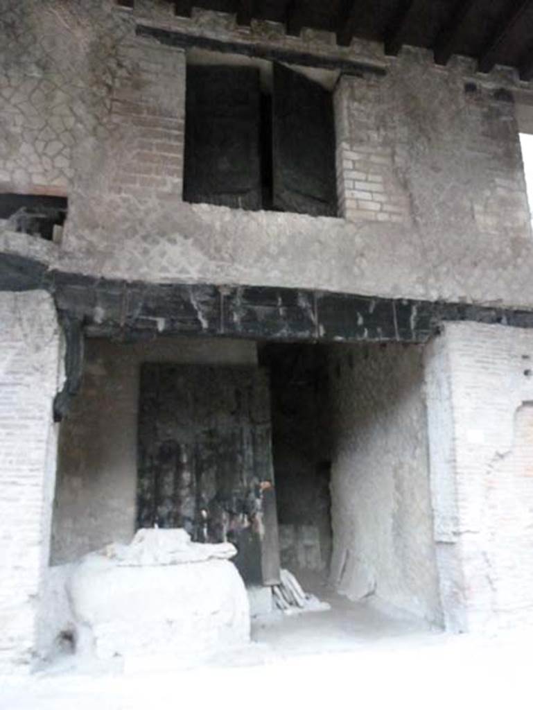 Decumanus Maximus, Herculaneum, September 2015. Building on north side of the Decumanus Maximus, doorway numbered 4 with the remains of door and window shutters in carbonised wood. Found on the left, partially buried in the volcanic debris and left in situ, was a large wooden chest with lid and rear in iron, inside of which were some bronze pots/vases.
See Camardo, D, and Notomista, M, eds. (2017). Ercolano: 1927-1961. L’impresa archeologico di Amedeo Maiuri e l’esperimento della citta museo. Rome, L’Erma di Bretschneider, (p.280-81, Scheda 56)
According to Guidobaldi,the pots/vases were made of glass.
See Guidobaldi, M.P, 2009: Ercolano, guida agli scavi. Naples, Electa Napoli, (p.118).  See Pesando, F. and Guidobaldi, M.P. (2006). Pompei, Oplontis, Ercolano, Stabiae. Editori Laterza, (p.385-6)
Found on the ground floor of Shop No. 4, on 8th January 1968 (New excavation on Decumanus Maximus), were –  Intaglio su corniola: Eros and Anteros, now in Naples Archaeological Museum, inv. no. 158866. (Pannuti 1983, 36).  Intaglio su corniola: Cavaliere, now in Naples Archaeological Museum, inv. no. 158867. (Pannuti 1983, 163).
See Pagano, M. and Prisciandaro, R., 2006. Studio sulle provenienze degli oggetti rinvenuti negli scavi borbonici del regno di Napoli.  Naples: Nicola Longobardi.(p.232).
See Pannuti, U. 1983. Museo Archeologico Nazionale di Napoli. Catalogo della collezione glittica. Rome. Vol.1. 
