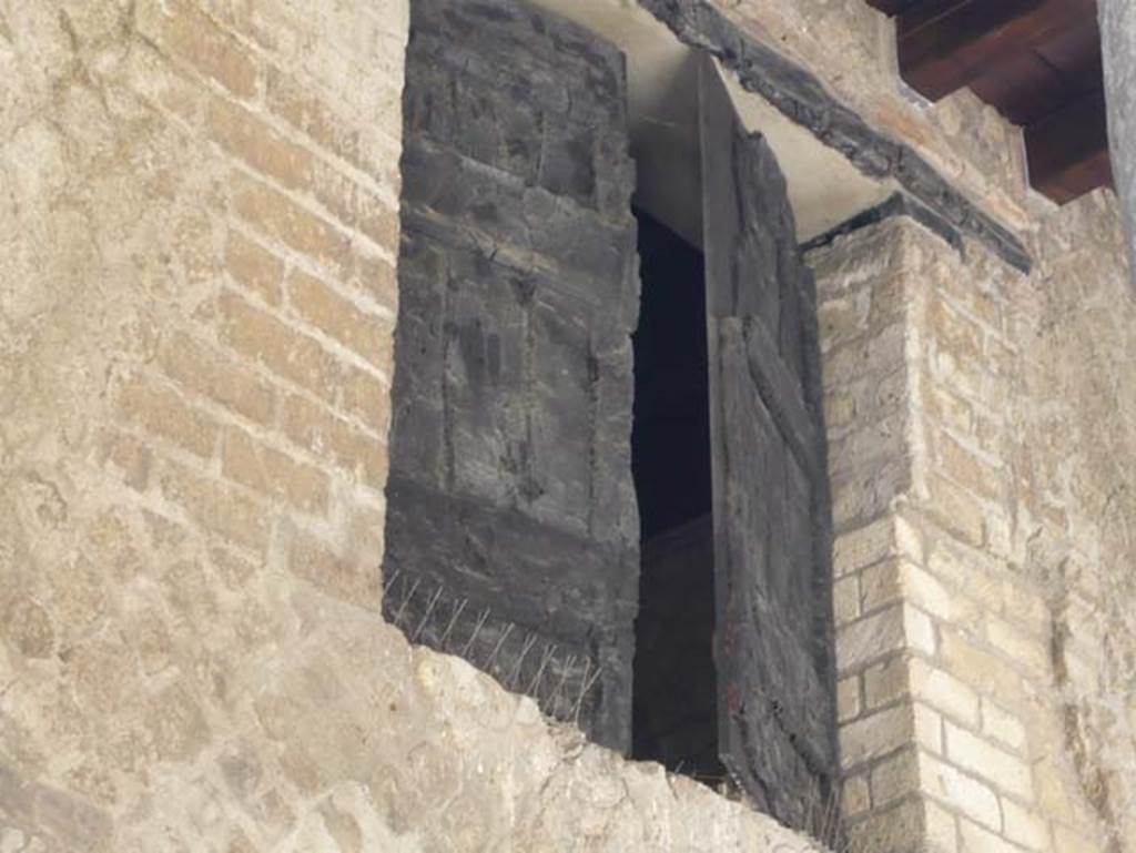 Decumanus Maximus, Herculaneum. August 2013. Detail of window shutter of carbonised wood, above doorway numbered 4.  Photo courtesy of Buzz Ferebee.

