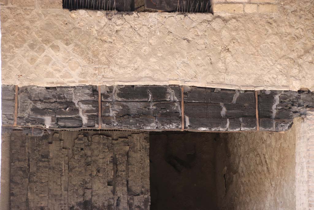 Decumanus Maximus, Herculaneum. October 2020. Detail of carbonised wood from above doorway numbered 4, and wooden shutter.
Photo courtesy of Klaus Heese.
