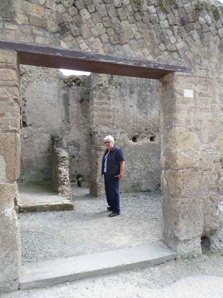 III.4 Herculaneum. May 2010. Doorway to shop, workshop or small house on east side of Cardo III Inferiore.  Looking east towards area leading to recesses on left, and two rooms on right.
