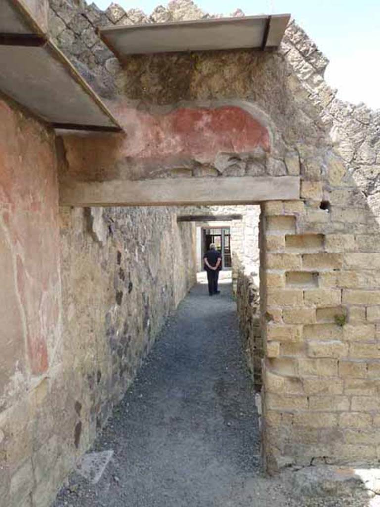 IV.8, Herculaneum, May 2010. Looking west along corridor from the courtyard.
According to Pesando and Guidobaldi, above the inside of the opening that gave access to the courtyard 5 and to the room 6, there was a fresco, now lost, that
gave the conventional name to this house, here was shown a roll of papyrus (volumen) with the name in Greek of Eutychos and the typical elements of writing instruments, the inkwell and pen.   
See Pesando, F. and Guidobaldi, M.P. (2006). Pompei, Oplontis, Ercolano, Stabiae. Editori Laterza, (p.335-6).
According to Cooley and Cooley, in a painting of a papyrus scroll, the title can be seen written upon it in black letters, in Greek.  It read = Eutychos wrote verses with music.      (CIL IV 10481).
See Cooley, A.E. & Cooley, M.G. (2014). Pompeii and Herculaneum, a sourcebook.  Oxford, Routledge, 2nd ed. (p.101, numbered D84).
