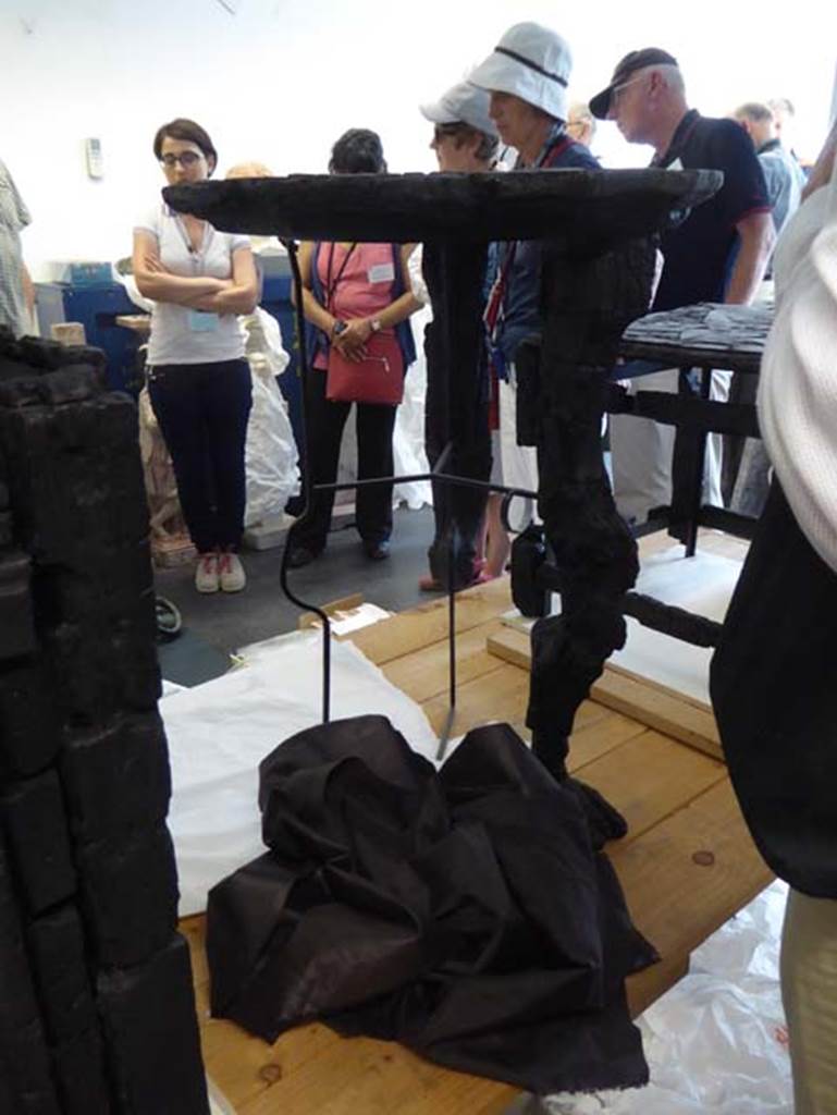 V.5 Herculaneum, September 2016. 
Carbonised wooden table with circular top and three legs decorated with greyhounds.
Photo courtesy of Michael Binns.
See De Carolis, E. (2007). Il mobile a Pompei ed Ercolano, letti tavoli sedie e armadi. Rome, “L’ERMA” de Bretschneider, (p.100). 
The location where table was found is not known by us, at present.
Many items of carbonised wooden furniture were found in this house, from which it was named.
See also different carbonised wooden table in Room 8.

