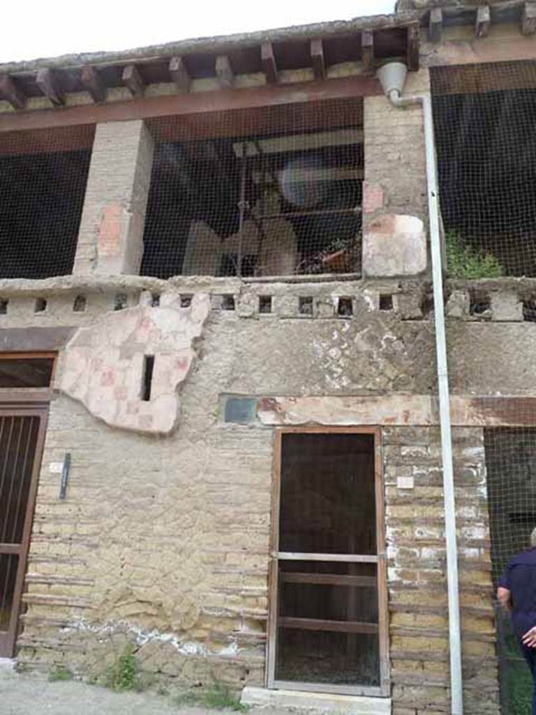 V, 14 in centre, Herculaneum, May 2010. Entrance doorway and upper floor.
The room at the back on the upper floor above the entrance doorway was the room where 150 waxed tablets of Calatoria Themis, wife of C. Petronius Stephanus, were found in a carbonized wooden box. The contents of the tablets were still readable and recorded the story of a roman law-suit, see V.15.

