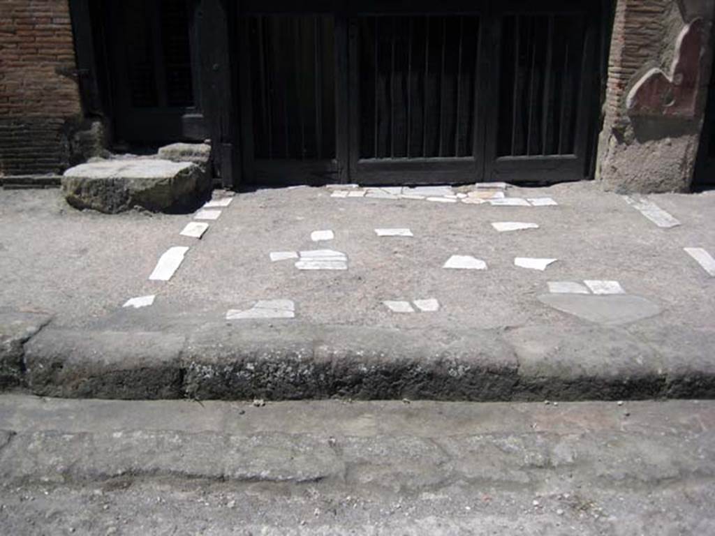 V.17 Herculaneum, June 2011. Pavement outside entrance to V.17, on right, and steps to upper floor at V.18, on left.
Photo courtesy of Sera Baker.
