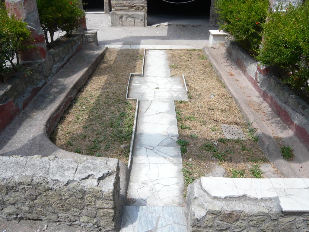 V.30 Herculaneum. August 2013. 
Looking west across atrium towards the shallow impluvium crossed by the channels of a cruciform fountain, at its centre.
Photo courtesy of Buzz Ferebee.
