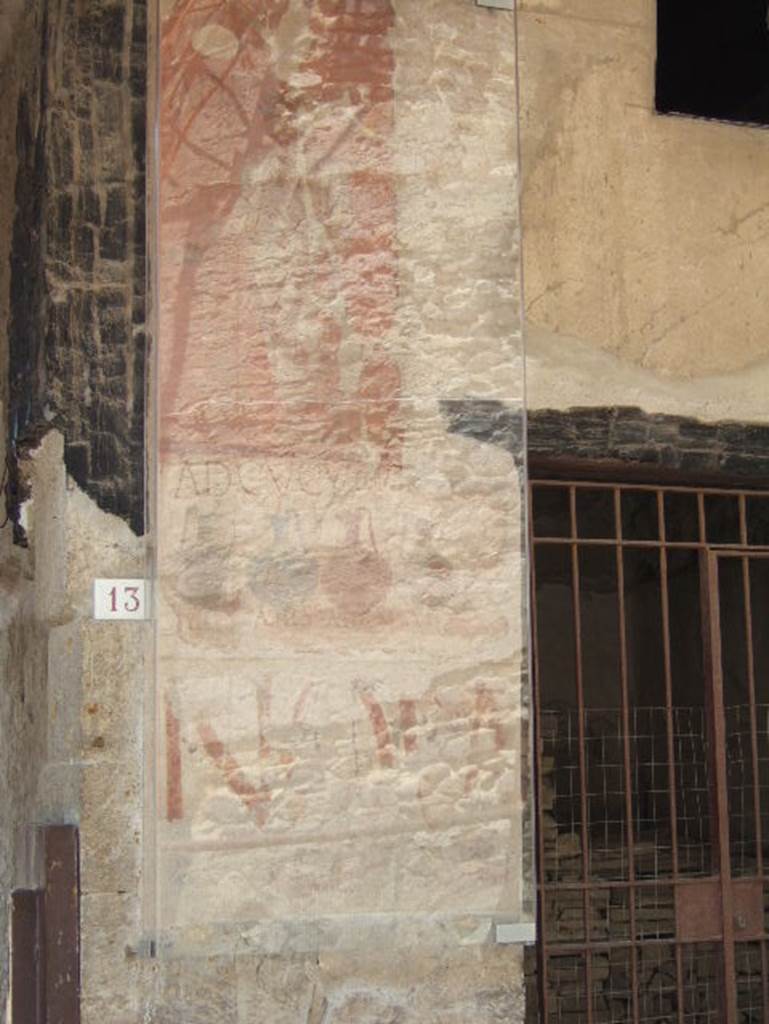 VI.13 Herculaneum on left, VI.14 on right. May 2006. 
Painted sign on pilaster between house entrance and shop. Looking south.
At the top is a painted figure. 
The shop sign showed four jugs of different colours, naming and pricing the drinks sold here together with the shop sign AD CVCVMAS (Ad Cucumas), written above the jugs.
The painted graffiti NOLA in red letters can also be seen on the lower part.