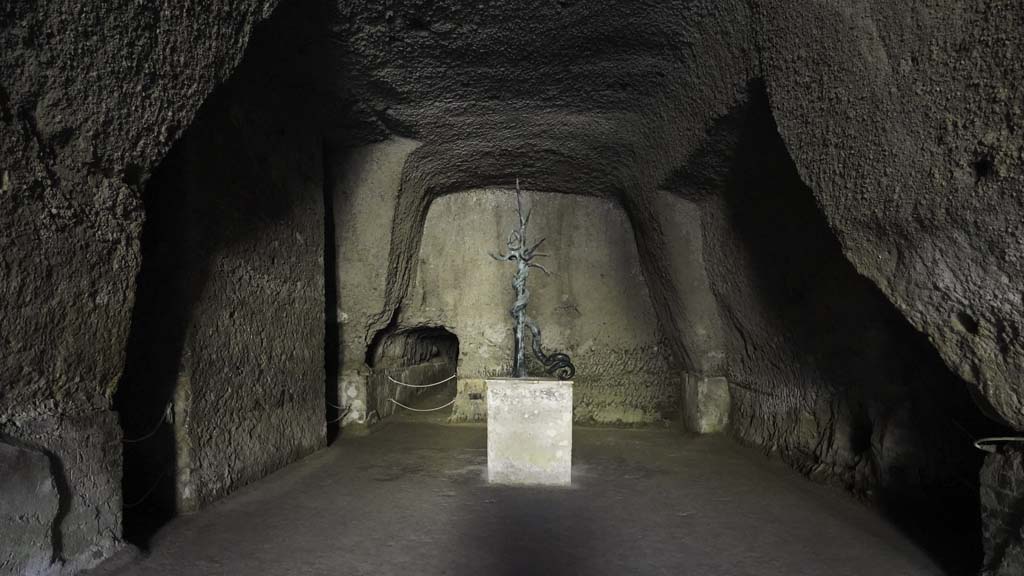 Ins. Orientalis II.4, Herculaneum, August 2021.  
Looking into the cavern, which would have been the site of the playing field of the Palaestra. Photo courtesy of Robert Hanson.
According to Deiss, 
“In the centre of the field was a swimming pool in the form of a cross, some 160 feet in length and with an intersecting arm of 100 feet.
At the ends were fountain jets. In the centre was a giant bronze serpent, coiled on the limbs of a tree, and from whose five crowned heads water sprayed into the pool. The serpent, which was overlooked by the Bourbons, has been restored to its commanding position.
The mountain of hard mud has not been removed from above the cruciform pool, but merely hollowed out like a cavern over the central portion.”
See Deiss, J.J. (1968). Herculaneum: a city returns to the sun. London, History Book Club, (p.128).
