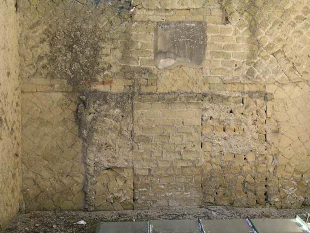 Ins Or II, 16, Herculaneum. May 2004. Room at rear of Ins.Or.II.16, but part of Palaestra at Ins. Or. II.4, detail of west wall. 
Photo courtesy of Nicolas Monteix.
It was clear to Maiuri that the rooms of this workshop originally would have formed a single large entrance to the loggia of the cryptoporticus of the Palaestra, which then came to have a larger and more independent entrance from Cardo V, at Ins.Or.II.19. Access from that entrance to the loggia allowed the abolition of this entrance, and it was then transformed into a poor and cramped workshop, with a small rear room and perhaps a dwelling on the upper floor above this room of the Palaestra. 

