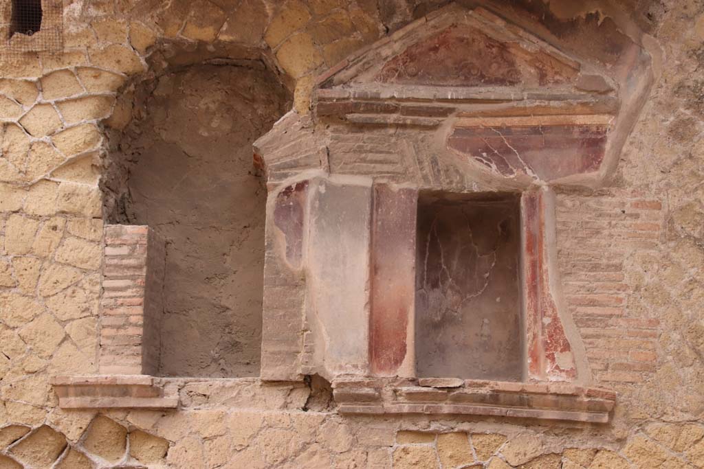 VI.29 Herculaneum. October 2020. Atrium 9, detail of lararia on south wall. Photo courtesy of Klaus Heese.
According to Maiuri –
“Nella Parete meridionale, accanto all’impluvio, sono incassate due nicchie di Larario, affiancate, in forma di edicole con frontoncino triangolare di coronamento: la meglio conservata ha, oltre al frontoncino, una cornicetta di laterizio e la sua originaria decorazione a fondo rosso.” 
(In the southern wall, next to the impluvium, there are two niches of the Lararium, side by side, in the form of aediculas with a crowning triangular pediment: the best preserved has, in addition to the pediment, a small brick cornice and its original decoration with a red background.)
See Maiuri, A., 1958. Ercolano, I Nuovi Scavi, (1927-1958). Vol.1. Roma: Inst. Poligrafico dello Stato, (p.279).
