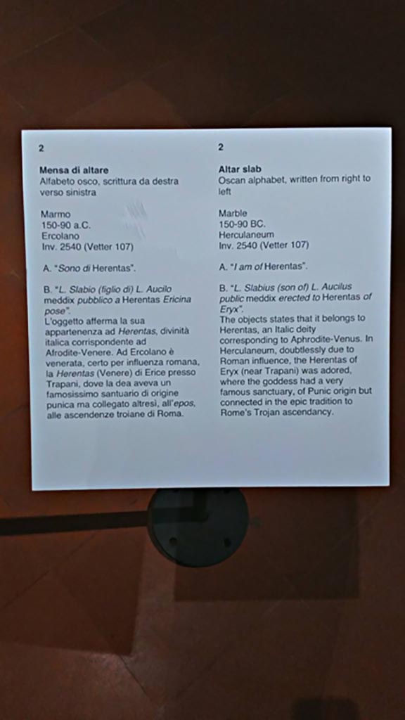 Herculaneum, information card from Naples Archaeological Museum, inv. 2540 (Vetter 107).
Photo courtesy of Giuseppe Ciaramella, June 2017.

According to Guidobaldi-
“La prima sistemazione dell’area risale probabilmente all’età augustea, ma già nell’età preromana, in forme che non sono al momento note, doveva essere qui praticato almeno il culto di Venere, come testimonia l’unica iscrizione in lingua osca restituita dalla citta, quella sull’altare della dea Herentas Erycina
(Herentas è il corrispettivo osco di Venere), fatto fare da Luvkis Slabis Aukil, sommo magistrato del periodo sannitico (meddiss tuvtiks).
Gli edifici di culto furono profondamente restaurati dopo uno dei terremoti che sconvolsero l’area vesuviana nei 17 anni precedenti l’eruzione.”
See Guidobaldi, M.P. (2009). Ercolano, guida agli scavi. Electa Napoli, (p.37).
(trans:
The first arrangement of the area probably dates back to the Augustan age, but already in the pre-Roman age, in a form that is not currently known, the cult of Venus, at least, would have been practised here, as evidenced by the only inscription in the Oscan language returned from the city, the one on the altar of the goddess Herentas Erycina (Herentas was the Oscan equivalent of Venus), made by Luvkis Slabis Aukil, high Magistrate of the Samnite period (meddis tuvtiks).
The buildings of the cult were extensively restored after one of the earthquakes that devastated the Vesuvian area in the 17 years preceding the eruption.”)

