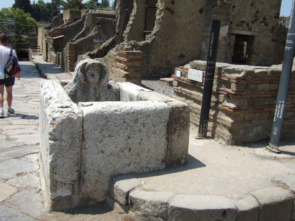 Cardo V Inferiore, Herculaneum. May 2010. 
Looking south towards fountain on corner of Ins. IV, at junction of Decumanus Inferiore, on right, and Cardo V Inferiore, on left. 
Entrance doorway to bar at IV.16, on the right
.
