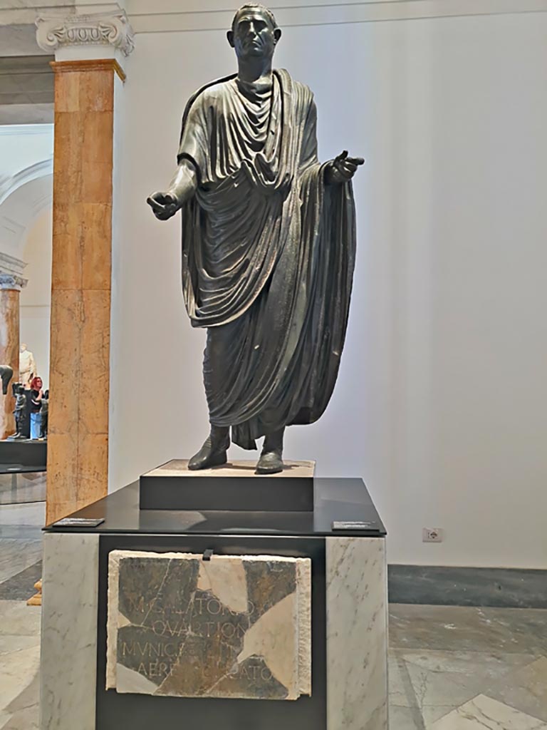 Herculaneum theatre. April 2023. Above - Bronze statue of Marcus Calatorius Quartio, inv. 5597.
Below – Dedication on marble slab, inv. 3730. 
On display in “Campania Romana” gallery in Naples Archaeological Museum. Photo courtesy of Giuseppe Ciaramella.
