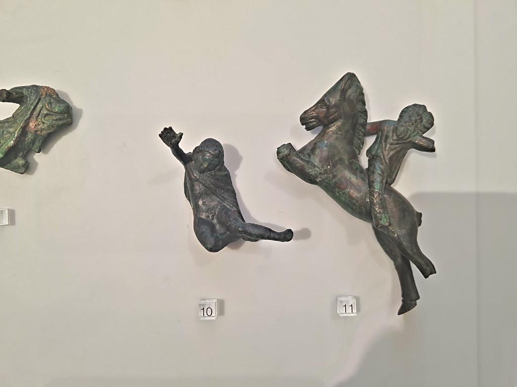 Herculaneum, April 2023. Bronzes in “Campania Romana” gallery in Naples Archaeological Museum. 
Detail of bronze figures in glass case - small bronze chariot attachments. Photo courtesy of Giuseppe Ciaramella.
