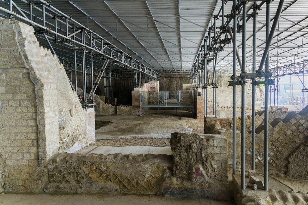 Herculaneum Villa dei Papiri. October 2023. Looking towards east wall of room (r), at the rear of room (s), on right. 
Ahead is the area of room (d) the west ala, and atrium (c), looking towards the room (e), the east, with painted remains in north-east corner.
Photo courtesy of Johannes Eber. 

