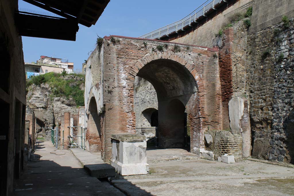 Decumanus Maximus, Herculaneum. March 2014. Looking west towards four-sided Arch. 
The drainage channel in front of the arch is  covered with stone blocks.
Foto Annette Haug, ERC Grant 681269 DÉCOR.

