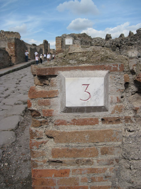 I.3.3 Pompeii. September 2010.  Looking east towards entrance doorway from across Via Stabiana.  Photo courtesy of Drew Baker.
According to Della Corte, this house was spacious and beautifully decorated, with temple-lararium in the atrium and peristyle on a higher level than the atrium.
Della Corte believed the house was owned by Epidius Fortunatus, because an amphora was found here, still containing honey in it, addressed to -
Mel P() P() CXXXIII
dat XXXXXIX s(emissem)
Epidio Fortunato
/
T() P() XXVIII
[…]ens              CIL IV 5740
See Della Corte, M., 1965.  Case ed Abitanti di Pompei. Napoli: Fausto Fiorentino. (p.264)

