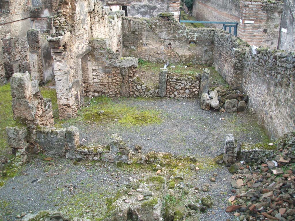 I.6.13 Pompeii. December 2004.  West side looking south, photo taken from rear of I.6.11.
Triclinium 4 would appear to be the large room across the centre of the photo.
Room 7 can be seen on the lower left, room 10 on the lower right.
On the north side of room 10, (but not in the above photo) would have been a small room.
This was described on page 433 of Notizie degli Scavi, 1929, -
“as a second corridor “f” used to separate the narrow rooms 8-9-10 and corresponding to a side doorway to the western vicolo, with a wooden staircase giving access to the upper floor, a doorway that would have been closed or abolished at the time of the abandonment of the house, after the 63 earthquake.”
Room 9 would have been a small room in the north-west corner of the house.
