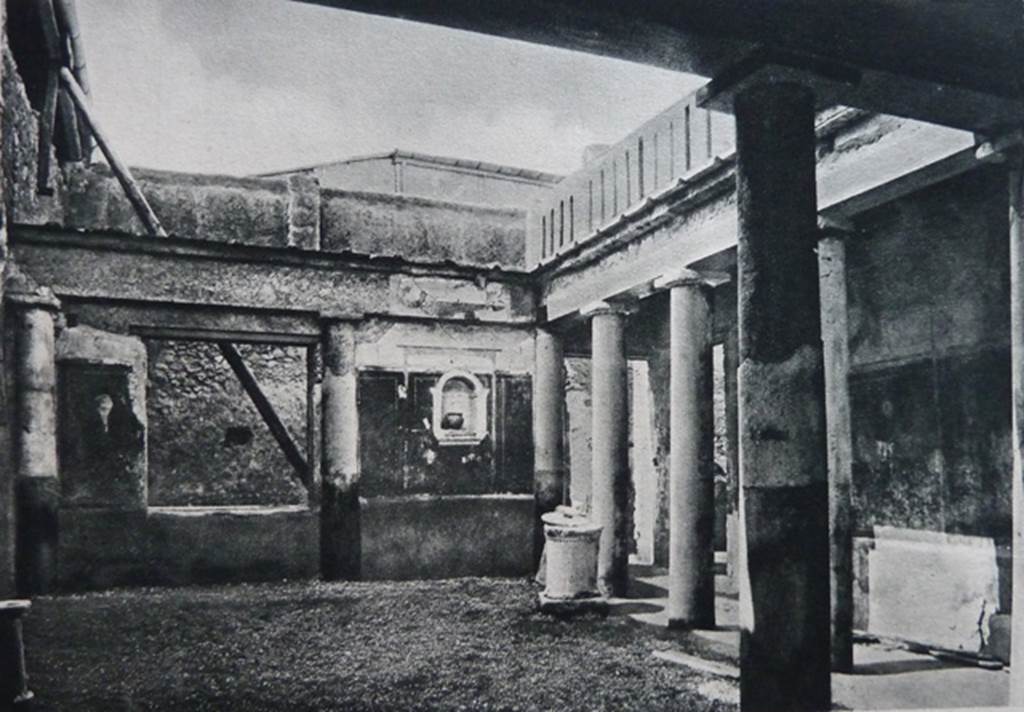 I.7.7 Pompeii. Old undated photograph. Pseudoperistyle, with lararium niche seen in west wall. According to Boyce, the arched niche was adorned with a stucco aedicula façade and a cornice running around the inside walls. The area of the wall immediately around the niche was painted as part of the decoration, into which the niche was set in a panel. There was no lararium painting and no other indication of religious use. It is called an edicoletta larare in the report and probably was a shrine, as there is none elsewhere in the house. Not. Scavi, 1927, 27.
See Boyce G. K., 1937. Corpus of the Lararia of Pompeii. Rome: MAAR 14. (p.25, no.39) 
