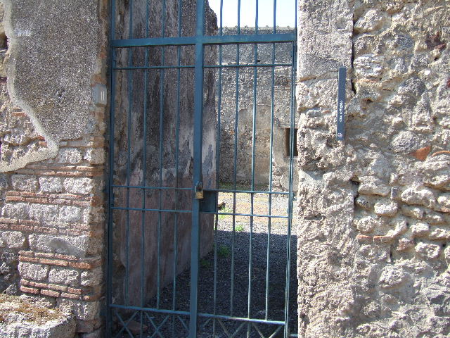 I.7.11 Pompeii. December 2006. South end of house, north wall of north portico with reproduction wooden doors, leading from I.7.12. According to Jashemski, Maiuri said the space between the columns and the west pillar of the portico were closed by glass set in a wooden frame. This would have kept the rain and sun from the triclinium, tablinum and exedra. Maiuri did not mention finding any glass and some scholars think that wooden shutters were used. See Jashemski, W. F., 1993. The Gardens of Pompeii, Volume II: Appendices. New York: Caratzas. (p.38)
From now on, the photos show the northern part of this house, starting from the north wall of the north portico. To see the southern part of the house and garden area, see I.7.12

