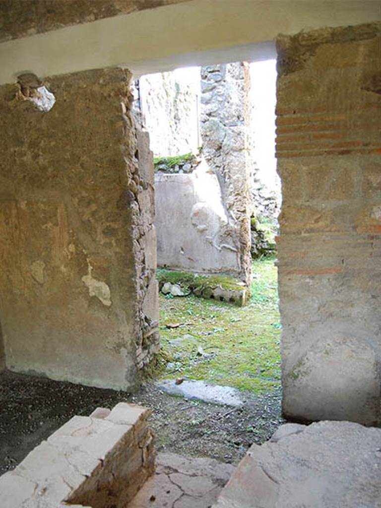 I.8.15 Pompeii. October 2013. Doorway on west side (on left side) of shop-room leading to rooms probably for the use of the customers. Through this room was another doorway which led into the rooms (at I.8.16) which were the kitchen, a triclinium, and another cubiculum. Photo courtesy of Paula Lock.
See Rivista di Studi Pompeiani, Vol III, 1989, article by Castiglione, V., Del Franco, M., and Vitale, R: “L’insula 8 della Regio I, un campione d’indagine socio-economica”, (p.185-221).
