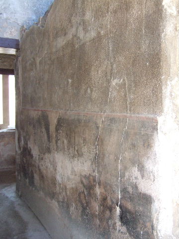 I.11.16 Pompeii. September 2005. Room 1, south wall of entrance fauces. On the right of the photo would be the room 2, stairs to the upper floor. According to Packer, a window which retained its ancient iron grill lit the stairs. This small window is visible on the south side of the entrance doorway in the photo of the façade. According to Packer, the stairs would have led to the area above rooms 1, 2, 4 and 5. Indications in the plaster of room 4 prove that the room above it also included the space over the fauces, room 1, and that this upper area may have been either a cubiculum or a small dining room. It certainly had at least one couch, as shown by the bed niche over the east doorway of room 4. Marks in the plaster of the west wall suggest that the space over the western half of room 5 was a single chamber lit by a window overlooking the vicolo. The plaster on the east wall demonstrated that this half of the upstairs room was divided into two small chambers, each 1.37m wide, separated by a partition 0.27m wide. The two small rooms over the east half of room 5 were both painted red.
See Packer, J: Inns at Pompeii: a short survey, in Cronache Pompeiane IV-1978 (p.18-24, see page 23, and 24).


