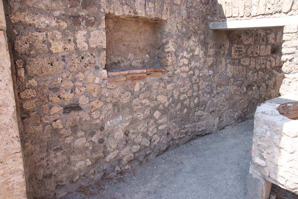 V.1.5 Pompeii. September 2021. 
Looking towards west wall with square niche/recess and doorway into rear room. Photo courtesy of Klaus Heese.

