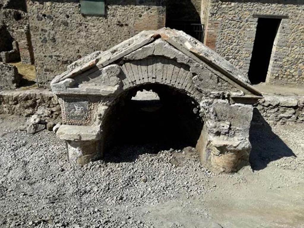 V.6.7 Pompeii. August 2018. Upper part of a fountain / nymphaeum.
The façade is facing the inside of the insula, where a garden probably opened. 
The surface so far exposed (upper part of the columns, upper part of the niche and pediment) is covered with vitreous tesserae and shells, which form complex decorative motifs. 
A bird is shown above one of the columns. Photograph © Parco Archeologico di Pompei.
