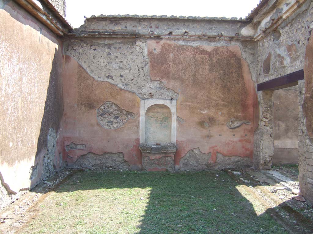 VI.2.22 Pompeii. September 2005. Aedicula niche in south wall of pseudo-peristyle. 
On the right is the doorway to the large triclinium.
According to Jashemski, this peristyle garden, excavated in 1811, was enclosed by a portico on the north and part of the east and west sides.
The portico was supported by five columns, red below, fluted and white above.
They were joined by a low wall.
There was an aedicula lararium (2.55m high) in the centre of the south wall.  
This once held a beautiful bronze statue of Apollo (Naples Archaeological Museum inv no: 5613). 
Dwyer pointed out that the Apollo was not found in the niche, however, but in the north colonnade of the peristyle, according to a report of Soprastante Pasquale Scognamiglio which Dwyer found in the archives of the Soprintendenza at Naples (VIII c8, Apr 3, 1811).
The Apollo was immediately reburied and discovered two days later in the presence of Queen Maria Carolina. 
An earlier report of Scognamiglio (Mar 21, 1811) mentioned a niche identical to the one in this house.  
But this house became confused with the one next door (VI.2.16/21) which became known as the House of the Apollo, and the statue was said to have been found there.  Dwyer points out that the only niche in the garden of VI.2.16/21 is modern, and it is only 0.67m high.
See Jashemski, W. F., 1993. The Gardens of Pompeii, Volume II: Appendices. New York: Caratzas. (p.122-3 and fig 134 for the Bronze Apollo).
