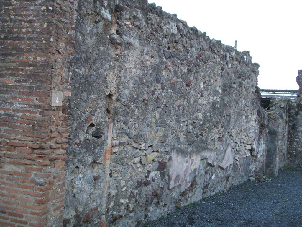 VI.4.4 Pompeii. December 2004. South wall from entrance.
According to Boyce, on this south wall, there was an outline of a large niche which seemed to have been originally a shrine.
This would have been opposite the lararium on the north wall.
This was probably filled in when the new shrine was painted.
See Boyce G. K., 1937. Corpus of the Lararia of Pompeii. Rome: MAAR 14.  (p.46, no.151)
A down-pipe can be seen in the wall.
