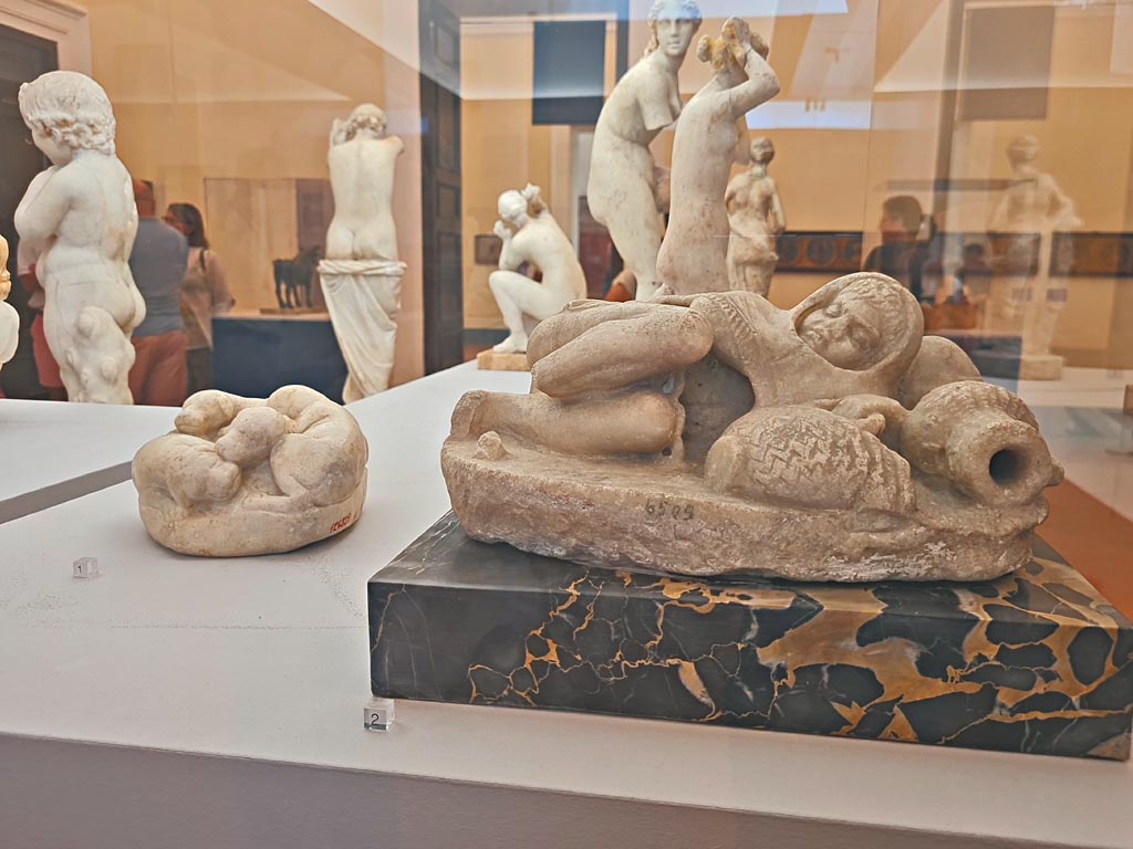 VI.8.23 Pompeii. October 2023. 
Marble statuette of a small sleeping fisherman, on right, found in the garden area at the side of the nymphaeum, inv. 6509.
On the left, marble block modelled into four puppies, found near small stairs in room 17 of VI.12.2/5 on 21/5/1895, inv. 124829. 
Photo courtesy of Giuseppe Ciaramella.
On display in “L’altra MANN” exhibition, October 2023, at Naples Archaeological Museum. 

