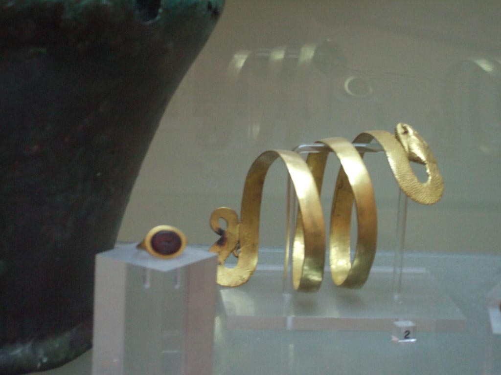VI.12.2 Pompeii. Found 4th March 1831. Gold bracelet with body of a serpent. 
Now in Naples Archaeological Museum. Inventory number 24824.
Gold ring with a virile nude figure and the inscription CAS-SIA.
Now in Naples Archaeological Museum. Inventory number 25136.
