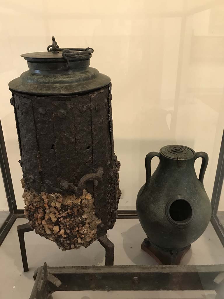 VI.12.5 Pompeii. April 2019. Iron stove with bronze lid, on left. 
Found in VI.12.2/5 on 21st March 1831 in a room around the atrium of the four columns (VI.12.5)
Now in Naples Archaeological Museum. Inventory number 264932.
See Fiorelli G., 1862. Pompeianarum antiquitatum historia, Vol. 2: 1819 - 1860, Naples, p. 249
Photo courtesy of Rick Bauer.
