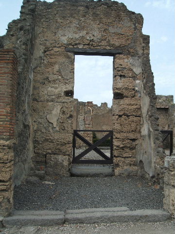VI.14.11 Pompeii. May 2005. Looking across shop to north wall with doorway to atrium of VI.14.12.
