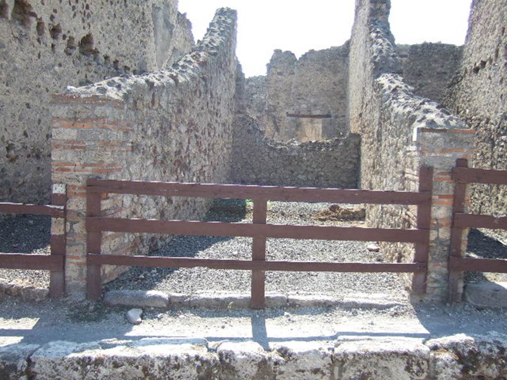 VI.14.26 Pompeii. September 2005. Looking west towards entrance doorway of workshop with a small rear room. According to BdI, the rear room was simply painted and reached by two steps in the middle of the west wall of the shop. To the right of these steps was the latrine. On the left was a large cauldron (deep 0.60 x 0.75 diam) embedded in a masonry structure, and under this the place for the fire, open at the front. Found here was a flagon and a casserole, both of bronze, a tripod that held a terracotta bowl, three dies (as in a game of dice), and four bronze coins. (18th May 1875). One could conclude that here was a thermopolium. See BdI, 1876, (p.45). 
