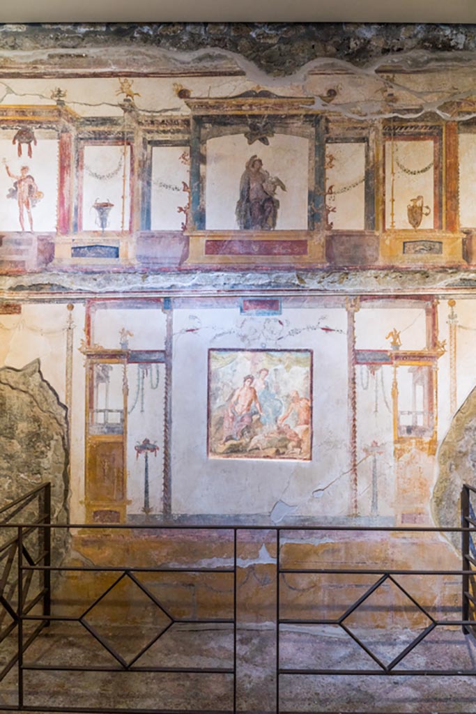VI.15.1 Pompeii. March 2023. 
Looking towards central panel of south wall with painting showing fight between Eros and Pan. 
In the upper centre is a painted aedicula containing Leda and the swan.  Photo courtesy of Johannes Eber.

