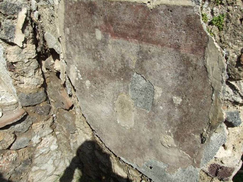 VI.15.6 Pompeii. March 2009. Room 9, east wall with remains of decorated plaster. According to NdS, to the right of the entrance doorway on the red stripe of the dado, an epigraph could be read.
