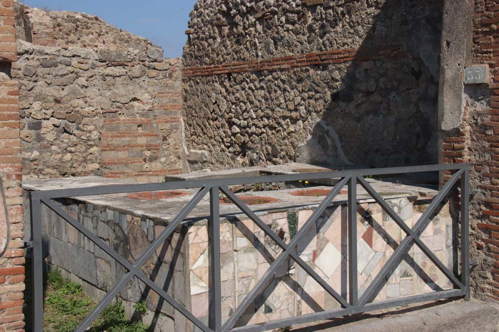 VII.2.33 Pompeii. September 2017. Looking north-east across entrance towards four-sided marble clad counter with seven built in urns.
Photo courtesy of Klaus Heese.
