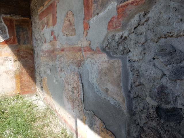 VII.7.5 Pompeii, May 2018. Oecus m, west wall in north-west corner. 
It is just possible to glimpse a female figure holding a plate of offerings in her left hand, on the black panel.
This would have been above a high zoccolo with panels of false painted marble.
See Sogliano, A., 1879. Le pitture murali campane scoverte negli anni 1867-79. Napoli: Giannini. (no.793)
Photo courtesy of Buzz Ferebee.
This would have been to the north of the doorway opening onto the east portico.

