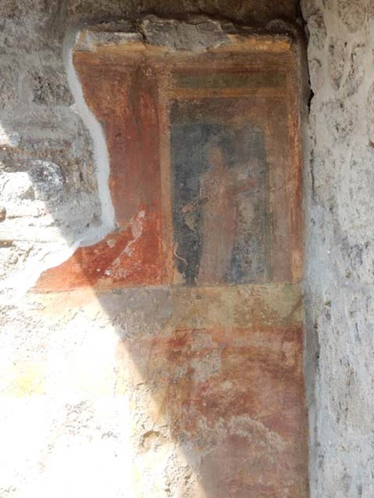 VII.7.5 Pompeii, May 2018. Oecus m, west wall in north-west corner. 
It is just possible to glimpse a female figure holding a plate of offerings in her left hand, on the black panel.
This would have been above a high zoccolo with panels of false painted marble.
See Sogliano, A., 1879. Le pitture murali campane scoverte negli anni 1867-79. Napoli: Giannini. (no.793)
Photo courtesy of Buzz Ferebee.
This would have been to the north of the doorway opening onto the east portico.

