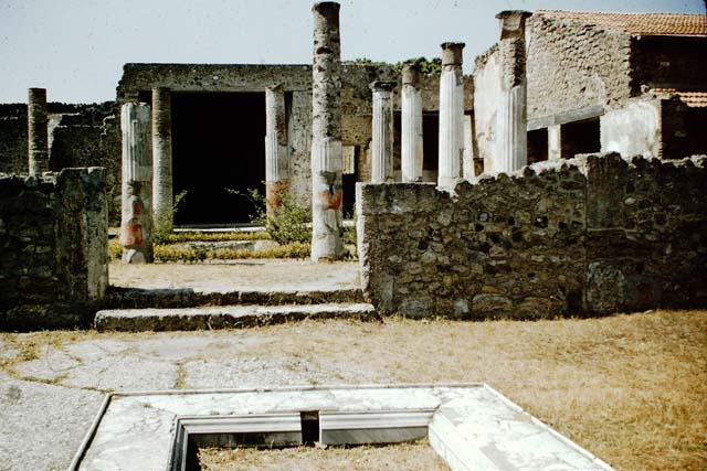 VII.7.5 Pompeii. September 2015. 
Looking across east side of atrium towards rooms (m), (n) and (o) on east side of peristyle and (q) and (r) in north-east corner.
According to Garcia y Garcia, this house had a beautiful marble impluvium in the centre of its atrium.
On the night of 24th August 1943, a bomb fell causing grave damage to this house.
It destroyed a part of the floor of the atrium and a good proportion of the rooms to the east and north-east of the peristyle.
Also destroyed was a part of the south and west of the portico, comprising of two columns with painted stucco.
The perimeter wall on the west, and three rooms on the north also fell, with the ruin of the best part of the painted fourth style plaster.
In the winter triclinium (n) on the east side of the peristyle, two important paintings that decorated it, were partially destroyed.
They were of Tryptolemus and the other of Venus, they have been restored in part. 
Tryptolemus was shown receiving the ears of corn from Proserpine.
Venus was shown arriving carried by a triton, with a cupid assisting her to descend to the shore.
A young woman was shown receiving her and making an offering upon a garlanded altar.
On the night of 13th September, this house linked to VII.7.2 was again hit by another bomb.
See Garcia y Garcia, L., 2006. Danni di guerra a Pompei. Rome: L’Erma di Bretschneider. (p.112-114 including photos)
