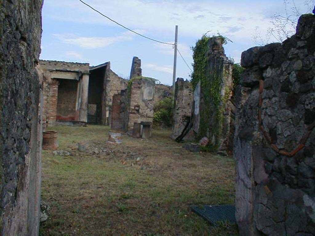 VII.7.10 Pompeii. September 2004. Looking north across atrium, from entrance fauces.
According to Boyce, against the west wall of the tablinum, near the entrance from the atrium, stood a high masonry base upon which may have rested the lararium.
See Boyce G. K., 1937. Corpus of the Lararia of Pompeii. Rome: MAAR 14. (p.68, no.297) 

