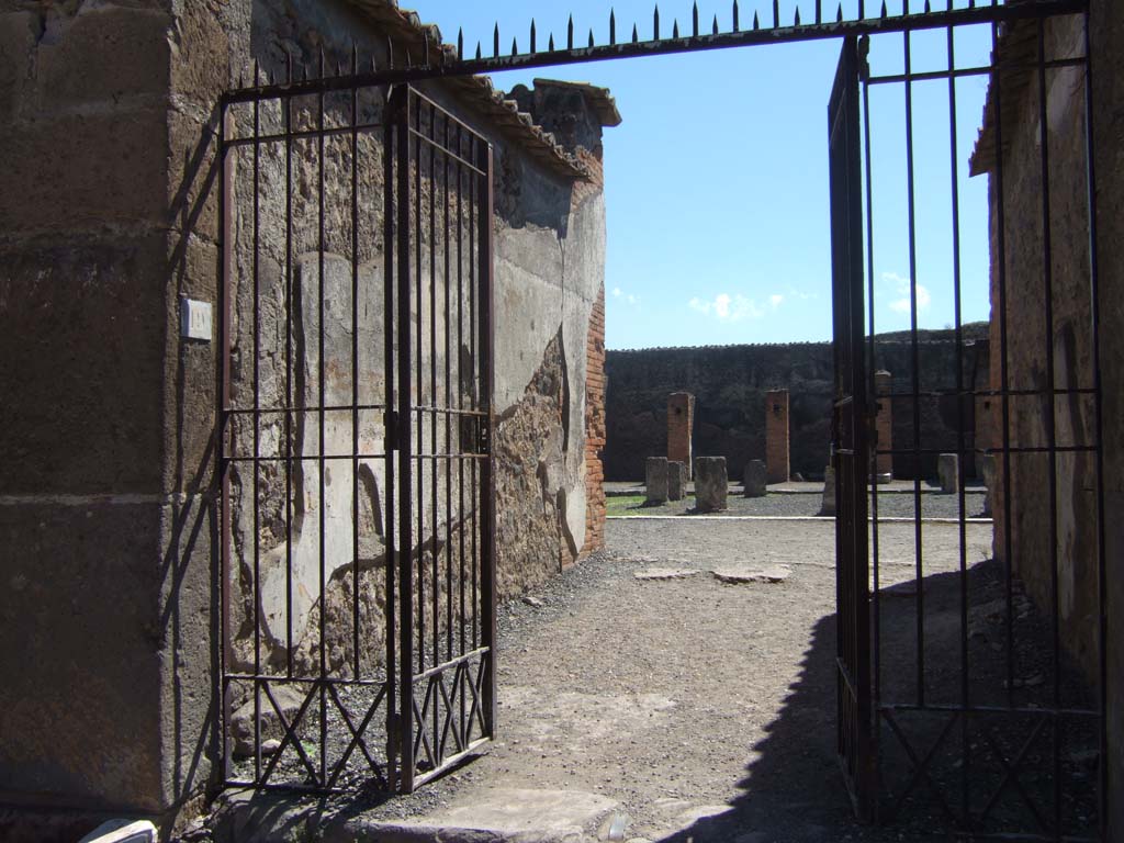 VII.9.19 Pompeii. September 2005. North entrance to Macellum on Via degli Augustali, looking south.  
According to Mau, somewhere amongst these shops and stalls to the north of the macellum, various charred foodstuffs were found.
Charred figs, chestnuts, fruits in glass vessels, plums, grapes, lentils, grain, loaves of bread and cakes were excavated.
See Mau, A., 1907, translated by Kelsey, F. W., Pompeii: Its Life and Art. New York: Macmillan. 
