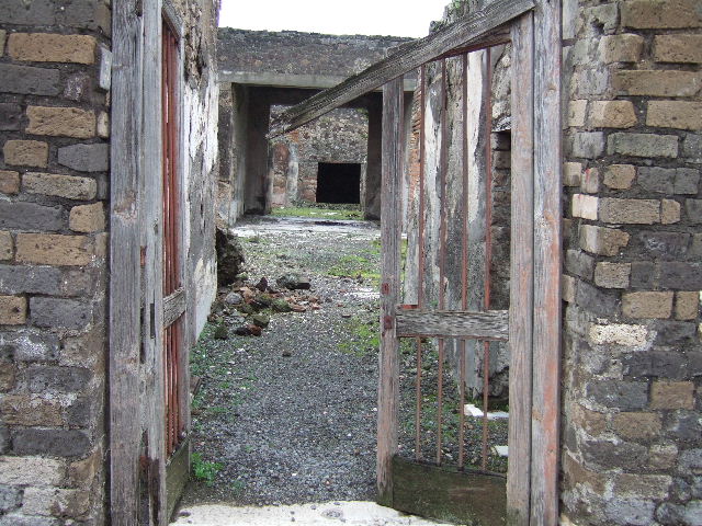 VII.10.3 Pompeii. December 2005. Atrium 3, with remains of impluvium and mosaic floor.
According to Amoroso, the impluvium was not in line with the entrance doorway. (p.44)
Originally the floor would have been in cocciopesto, but when the house was redecorated the atrium was given a new mosaic floor. The floor was composed of white tesserae with a border of two strips of three lines of black tesserae. (p.73)
Many of the rooms would have had a simple floor of cocciopesto, however, it should not be forgotten that certain rooms would have had floors and wall decorations of some merit and of these, now there is little visible trace. (p.59) 
The walls of the atrium would have been seen with a rich decoration of painted final IVth-style plaster. There would have been a high zoccolo (plinth/dado) composed of figurative panels on a white background, separated by yellow-ochre colour painted strips. The central area of the walls had a white background, subdivided into wide red and yellow panels, separated by a border. With regard to the plinth of the north wall, small square painted panels were documented. The decoration of the base of the south wall showed similar motifs to those on the opposite wall. A trace of a black dove was still visible on the top of the SE zoccollo. (p.73)
Studi della Soprintendenza archeologica di Pompei, 22: l”Insula VII, 10 di Pompei, by Angelo Amoroso, (p.44,59,73) 

According to Breton, the paintings from the atrium walls were almost all gone, but on the base of the walls it was still possible to see vases, a red partridge, some lions chasing bulls, dogs chasing a wild boar and a dog watching sheep. Several rooms around the atrium were fairly well decorated.
See Breton, Ernest. 1870. Pompeia, Guide de visite a Pompei, 3rd ed. Paris, Guerin. 

