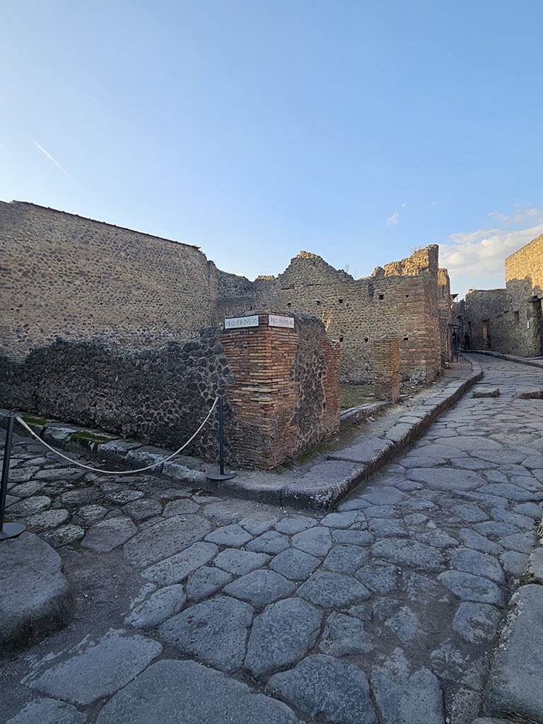 VII.11.17 and 16 Pompeii. November 2024. 
Looking north from junction to entrance doorways on Vicolo del Lupanare, in centre.
Vicolo degli Scheletri is on the left. Photo courtesy of Annette Haug.
