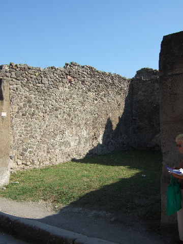 VII.12.10 Pompeii. September 2005. South wall with rear room of shop. On the right, were the stairs to upper floor and corridor to rear yard. According to Boyce, in the south-west corner of the rear area was a lararium. The lararium painting could be seen on the west wall of the kitchen above the hearth.
See Boyce G. K., 1937. Corpus of the Lararia of Pompeii. Rome: MAAR 14. (p.70, no.314)