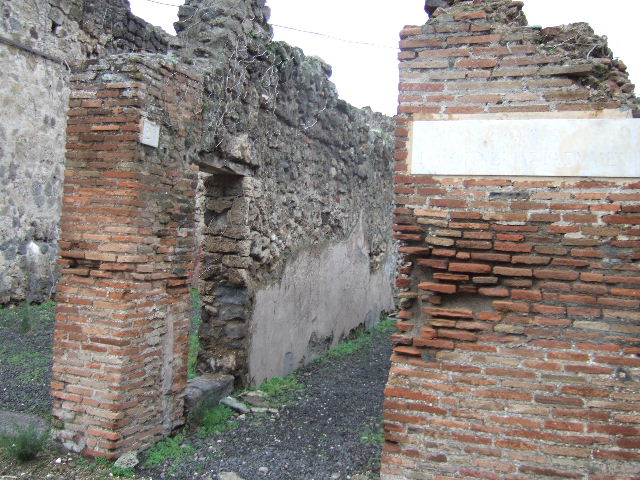 VII.12.26 Pompeii. December 2005. Fauces leading to small garden area at front of house. According to Jashemski, the garden at the front of the house was reached by a long corridor. It was enclosed on the north and east by a portico. This was supported by two columns and one engaged column which were joined by a low masonry wall. It had an entrance to the garden on both the north and east sides. According to Fiorelli, half the garden was cultivated, half of it was paved to provide a passageway to the portico. The triclinium on the north side had a fine view of the garden. A large window in the south wall of the garden gave light to the shop on the other side.
See Jashemski, W. F., 1993. The Gardens of Pompeii, Volume II: Appendices. New York: Caratzas. (p.196)

