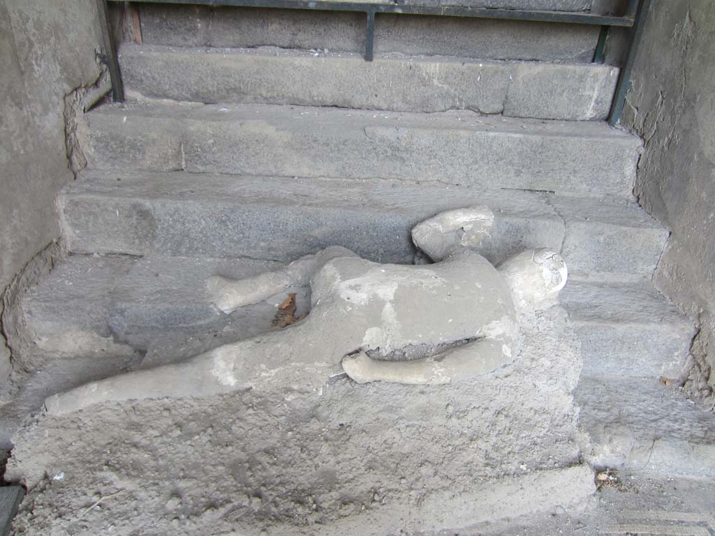 VII.16.17-22 Pompeii. May 2012. Plaster cast of body lying at foot of staircase. Photo courtesy of Marina Fuxa.