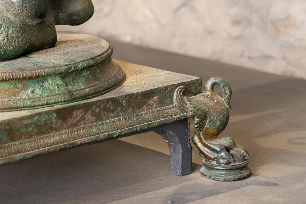 VII.16.17-22 Pompeii. January 2023. 
Oecus 62, detail of base of the bronze Ephebus, used as an oil lamp holder, found in dining room. Photo courtesy of Johannes Eber.
On display in exhibition in the Palaestra.
