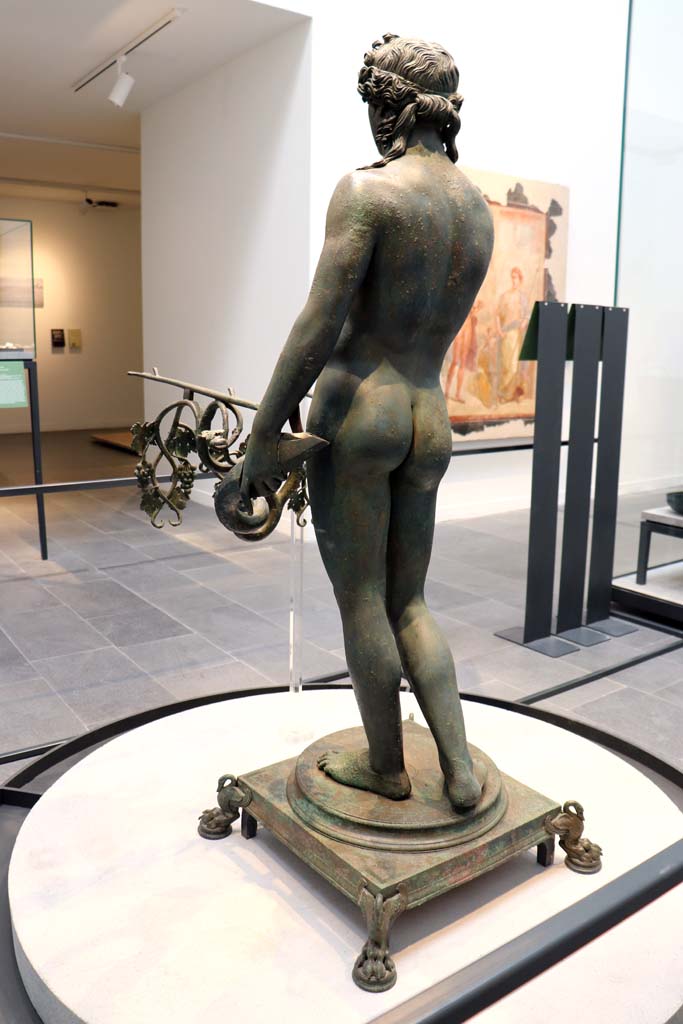 VII.16.17-22 Pompeii. February 2021. Oecus 62.
Rear of statue of the bronze Ephebus, used as an oil lamp holder, found in dining room.
Photographed on display in Antiquarium. Photo courtesy of Fabien Bièvre-Perrin (CC BY-NC-SA).
