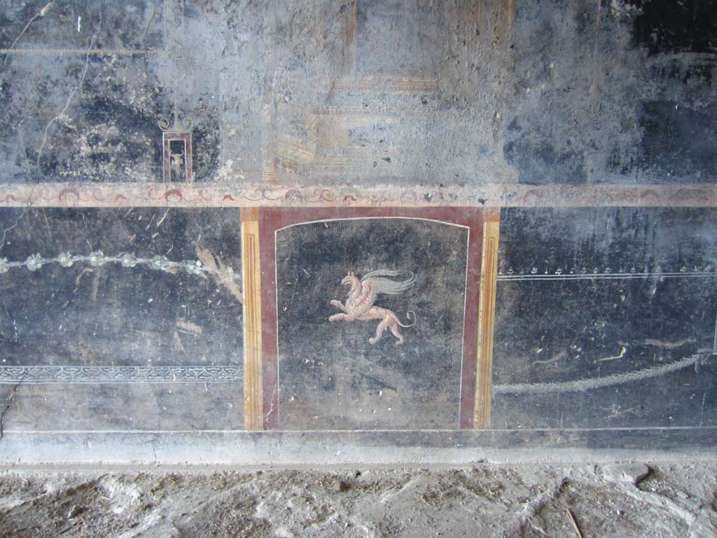 VII.16.17-22 Pompeii. May 2012. 
Oecus 62, wall decoration of flying griffin in a panel in the zoccolo/dado or lower plinth. Photo courtesy of Marina Fuxa.
